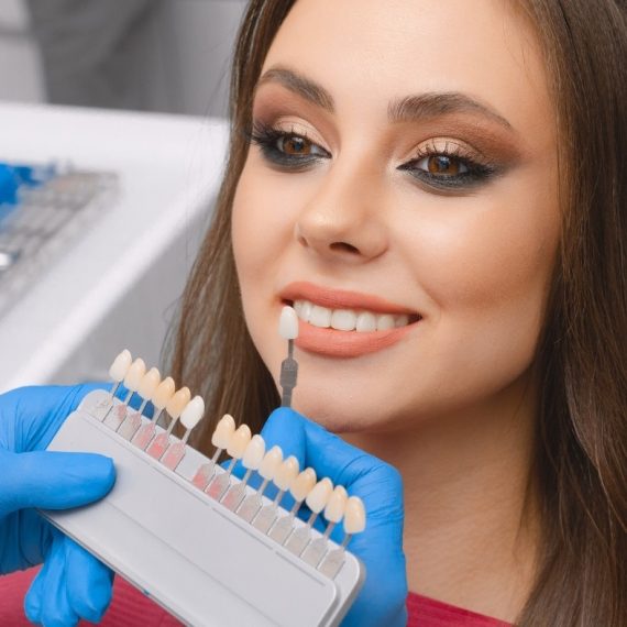 A woman sitting in a dentist's chair with a set of veneers.